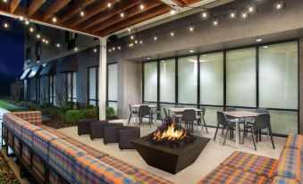 a patio area with a fire pit surrounded by chairs and tables , creating a cozy atmosphere at Home2 Suites by Hilton Long Island Brookhaven