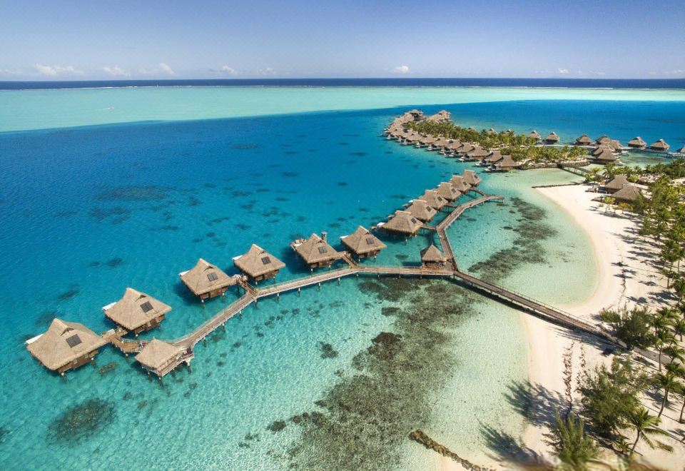 aerial view of a tropical island with a group of wooden huts on stilts , surrounded by clear blue water at Conrad Bora Bora Nui