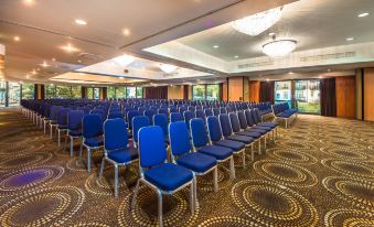 a large conference room with rows of blue chairs arranged in a semicircle , facing a projector screen at Holiday Inn London - Brentford Lock
