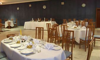 a large dining room with multiple tables set for a meal , featuring white tablecloths and chairs at Hotel Belvedere