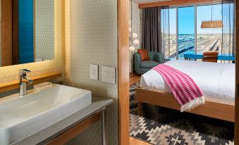 a hotel room with a bathroom , bedroom , and balcony , along with a view of the ocean at Hotel Indigo El Paso Downtown