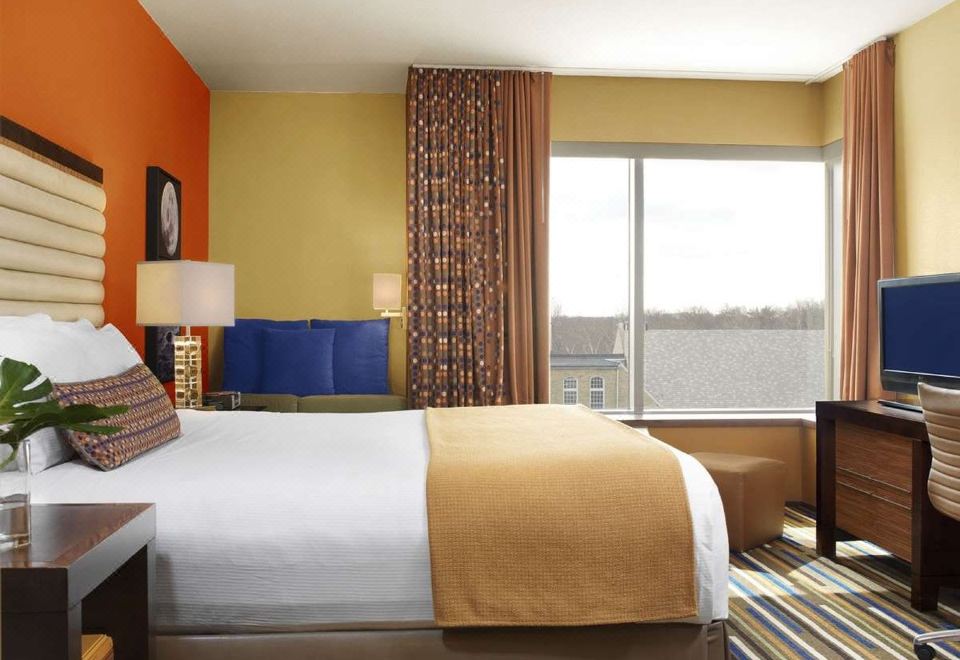 a large bed with a white comforter and brown throw is in a room with a window at The Moonrise Hotel