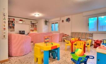 a colorful playroom with pink couches , chairs , and tables filled with toys for children to play with at Hotel Hamilton