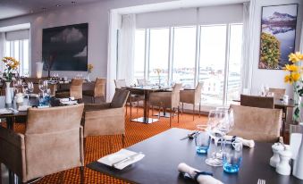a well - decorated restaurant with multiple tables and chairs , along with a view of the city through large windows at Hotel Hans Egede