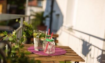 a wooden dining table with two glasses filled with water , one on the left and one on the right at Garden Apartment