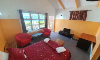 a cozy living room with a large bed , two chairs , and a tv . also a bathroom nearby at Le Uaina Beach Resort