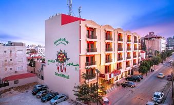 a large building with a red and white sign on the side , located in a city setting at Grand Hotel Madaba