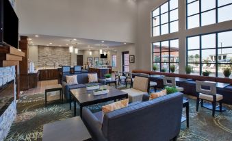 a large , well - lit room with multiple couches and chairs arranged in various positions , creating a comfortable seating area at Staybridge Suites Benton Harbor - ST. Joseph