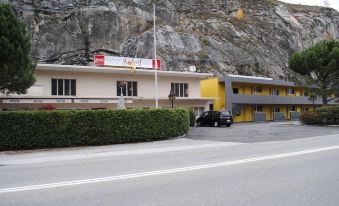 a building with a car parked in front of it and a large rock behind the building at Hotel du Soleil