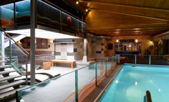 an indoor swimming pool with a diving board , surrounded by wooden walls and a glass fence at Hotel Berg
