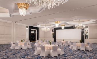 a large , elegant room with white tables and chairs set up for a formal event at The Ritz-Carlton, Doha