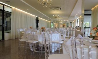 a large dining room with numerous white chairs and tables , some of which are set up for a formal event at Marina Park