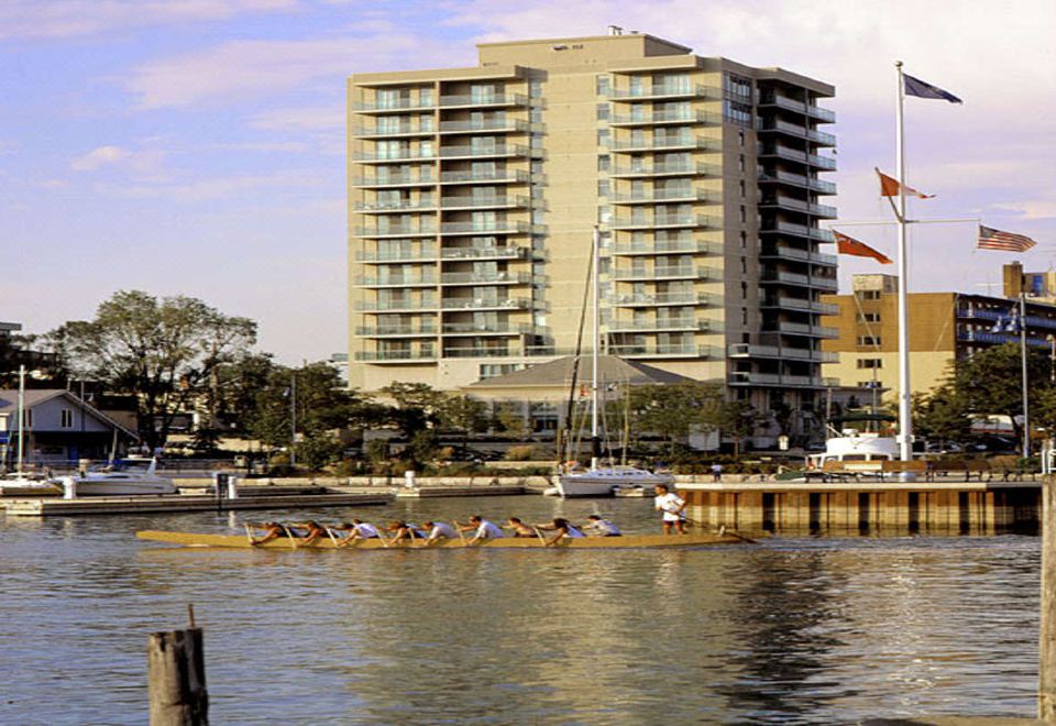 a group of people rowing boats in a body of water near a tall building at The Waterside Inn