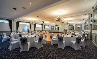a large banquet hall with multiple tables set up for a formal event , possibly a wedding reception at New Inn Hotel