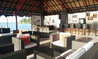 a large outdoor lounge area with couches , chairs , and a bar overlooking the ocean at Tasik Ria Resort