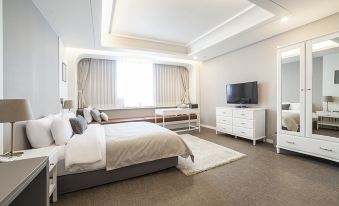 a modern bedroom with white walls , hardwood floors , and a large window overlooking the city at Polaris Hotel