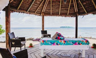 a woman is sitting on a massage table under a thatched roof , enjoying a day at the beach at Turtle Bay Lodge