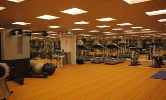 a large , well - lit gym with various exercise equipment such as treadmills , elliptical machines , and stationary bikes at Hotel Hans Egede