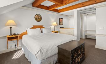 a large bed with white sheets and a wooden headboard is in a room with exposed wood beams at Trapp Family Lodge
