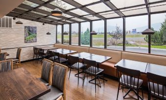 a modern restaurant with wooden floors , large windows , and a long dining table surrounded by chairs at Best Western Plus Butte Plaza Inn