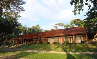 a large wooden building surrounded by trees , with a grassy area in front of it at The Pade Dive Resort