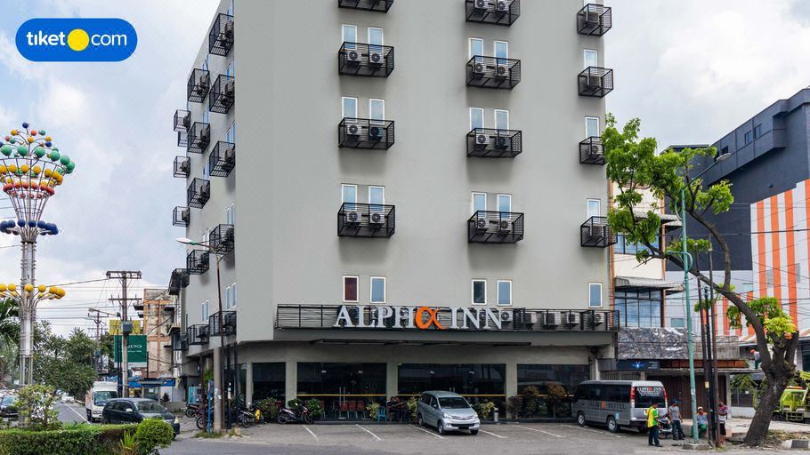 a tall building with multiple balconies and windows , as well as a parking lot in front of it at Alpha Inn