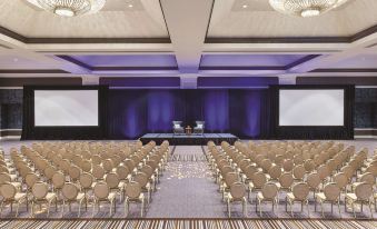 a large conference room with rows of chairs arranged in a semicircle , and a stage set up for an event at Signia by Hilton San Jose