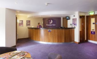 a reception desk with a person behind it and a sign for premier inn on the wall at Silverstone