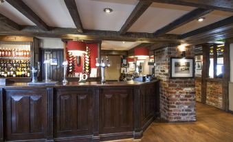 a bar with a wooden counter and chairs , surrounded by brick walls and a brick fireplace at Silverstone