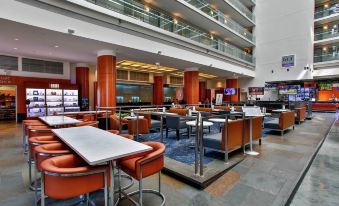 a modern lounge area with orange and white chairs and tables , large windows , and a television at Embassy Suites by Hilton Chicago Downtown Magnificent Mile