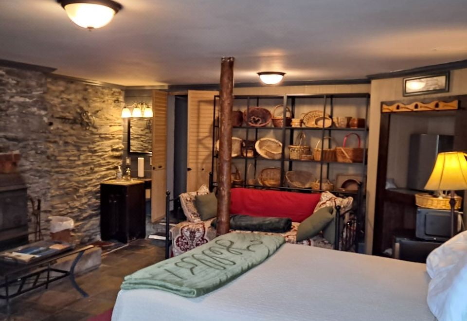 a cozy bedroom with a bed , a fireplace , and a brick wall , as well as a living room area with a couch and a dining at Town's Inn