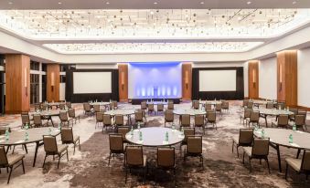 a large , well - lit conference room with round tables and chairs arranged for a meeting or event at Hilton Dallas Lincoln Centre