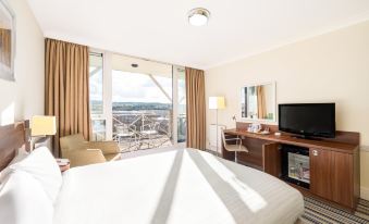 a modern hotel room with large windows , white beddings , and a balcony offering a view of the city at Holiday Inn Leeds - Brighouse
