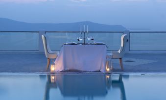 a table set up for two people at a rooftop pool , overlooking the ocean at night at Belvedere Suites