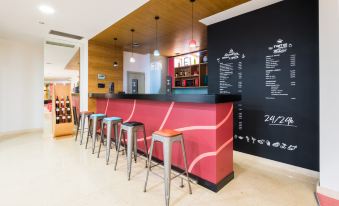 a modern bar with a red and black color scheme , wooden walls , and a chalkboard menu at Stay Hotel Guimarães Centro