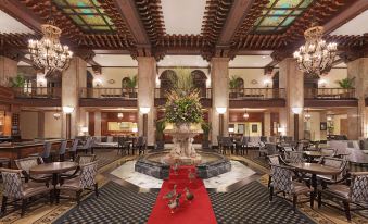 a large , well - lit hotel lobby with a red carpeted area and a fountain in the center at Peabody Memphis