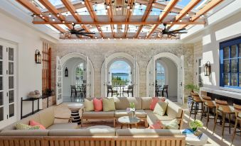 a large living room with a wooden ceiling , multiple couches , chairs , and a dining table at Rosewood Bermuda