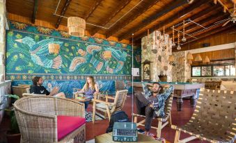 a man and a woman are relaxing in a lounge area with colorful chairs and a large mural at Selina Atitlan