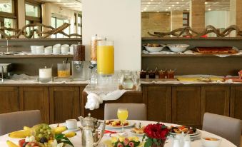 a well - set table with various food and beverages , including a pitcher of orange juice , surrounded by wooden shelves and white carpeted area at Hotel Antonios
