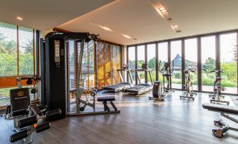 a well - equipped gym with various exercise equipment , including treadmills and weight machines , situated in a spacious room with large windows at Na Tree Tara Riverside Resort Amphawa Damnoensaduak