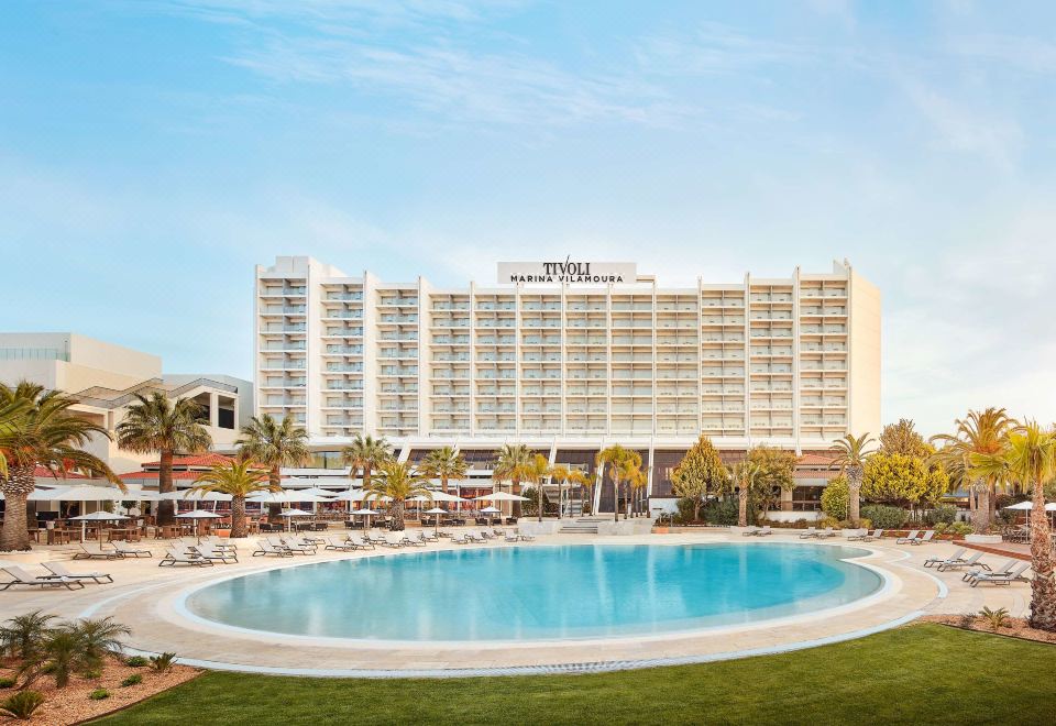 a large hotel with a pool surrounded by grass and trees , located in a resort area at Tivoli Marina Vilamoura