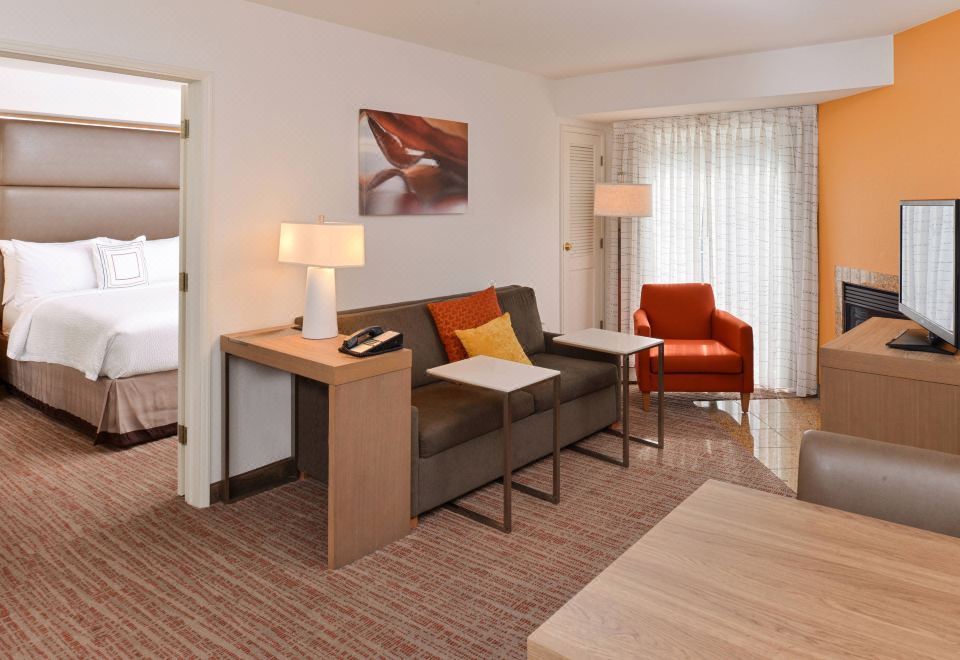 a modern living room with a couch , coffee table , and lamps , as well as a desk area at Residence Inn Palo Alto Los Altos