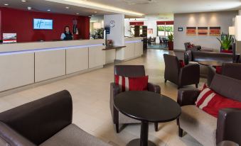 a hotel lobby with several couches and chairs , as well as a receptionist behind the counter at Holiday Inn Express London - Dartford