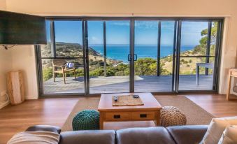a living room with a couch , coffee table , and sliding glass doors leading to an ocean view at Sea Dragon Kangaroo Island