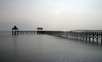 a wooden pier extending into a body of water , with a boat visible in the distance at Bromo Park Hotel Probolinggo