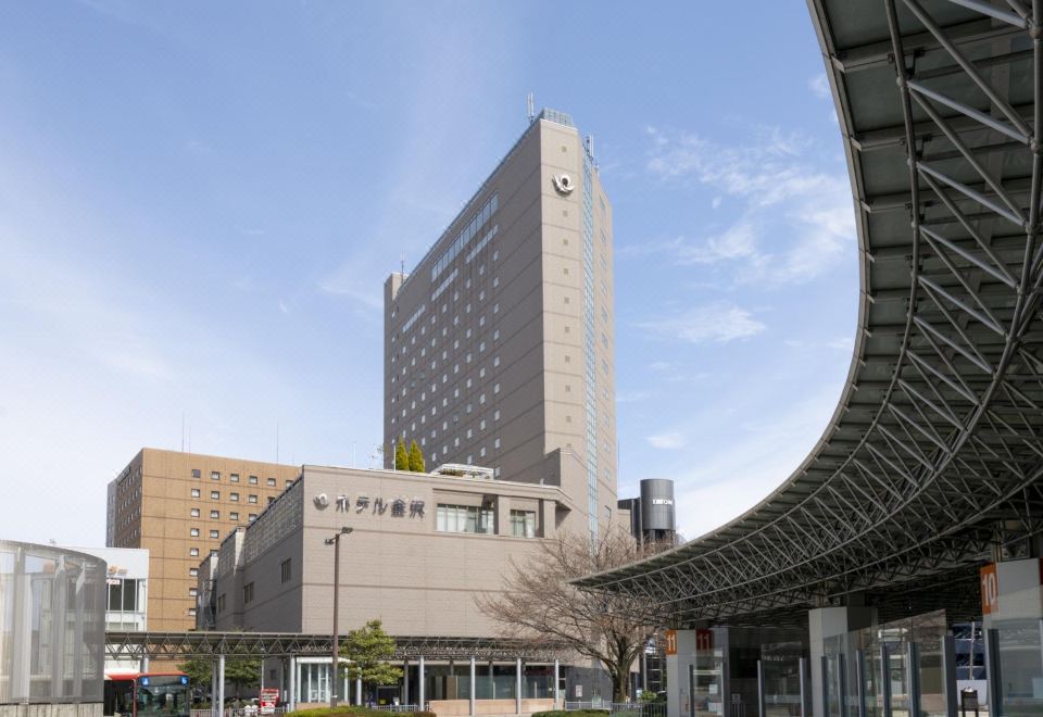 a tall building with a sign on the side is shown in front of another building at Hotel Kanazawa