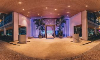 a large , well - lit room with a palm tree - lined entrance and a fish tank in the center at Radisson Blu Aruba