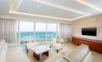 a modern living room with a large window overlooking the ocean , featuring white furniture and a wooden coffee table at Hotel Dann Cartagena
