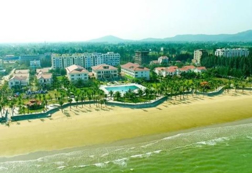a beach resort with a large pool surrounded by grass and trees , as well as a swimming pool in the background at Hai Tien Plaza Hotel
