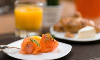 a plate of smoked salmon with dill and dill , next to a glass of orange juice at Hotel Moments Budapest